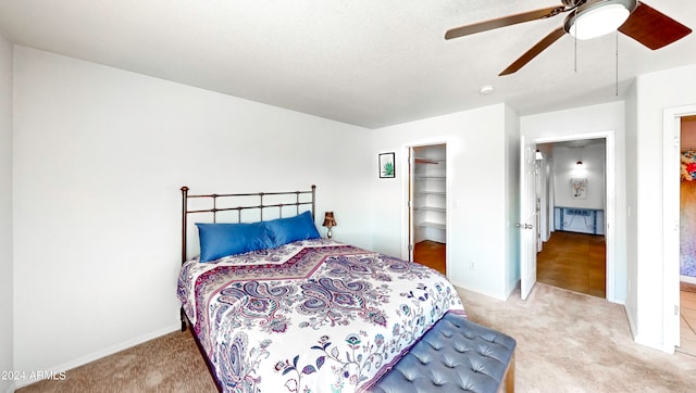 bedroom with carpet flooring, a textured ceiling, ceiling fan, a closet, and a walk in closet