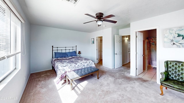 bedroom with ceiling fan, ensuite bath, and light colored carpet