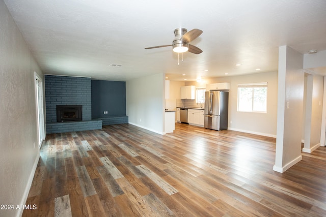 unfurnished living room with a fireplace, wood-type flooring, ceiling fan, and sink