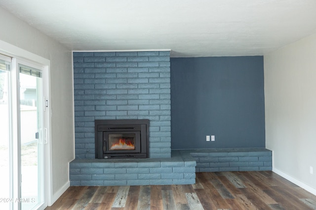 unfurnished living room with dark hardwood / wood-style flooring and a brick fireplace