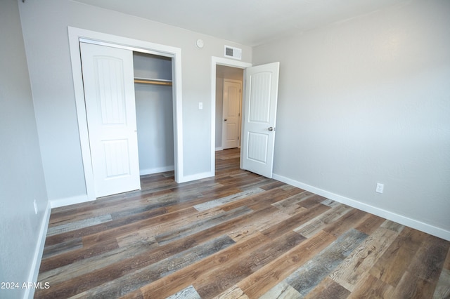 unfurnished bedroom featuring a closet and dark wood-type flooring