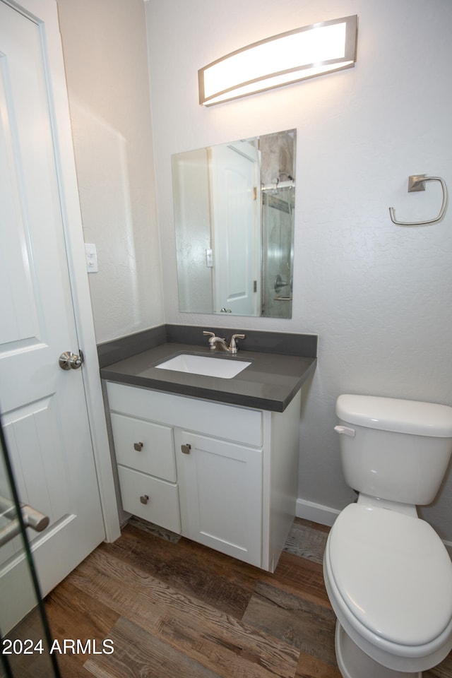 bathroom with toilet, vanity, and hardwood / wood-style flooring