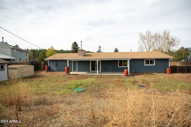 rear view of house featuring a shed, a patio area, and a lawn