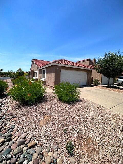 3510 E Hampton Ave Unit 133, Mesa, AZ 85204 - view of side of property with a tile roof, stucco siding, an attached garage, and driveway