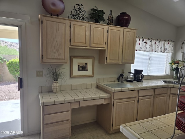 kitchen featuring light brown cabinets, a sink, vaulted ceiling, and light tile patterned floors