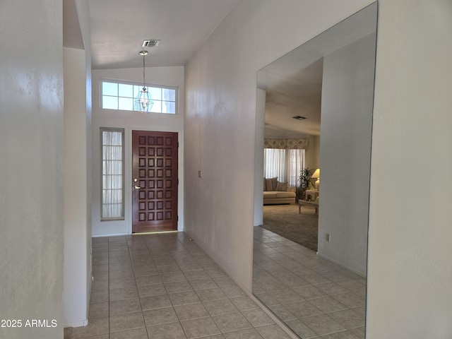 foyer featuring light tile patterned flooring, healthy amount of natural light, high vaulted ceiling, and baseboards