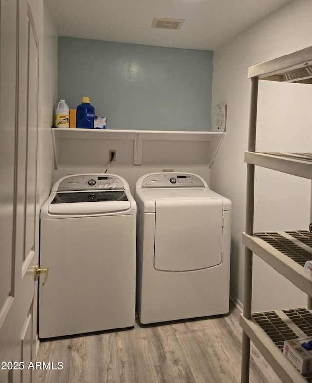 clothes washing area featuring washer and clothes dryer and light wood-type flooring