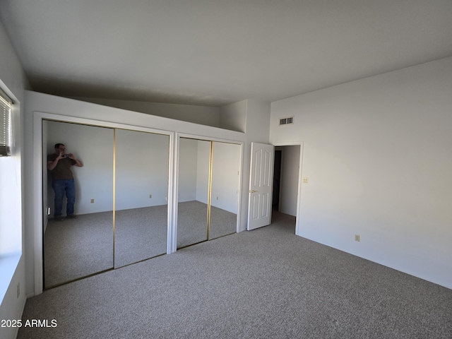 unfurnished bedroom featuring carpet floors, two closets, and vaulted ceiling
