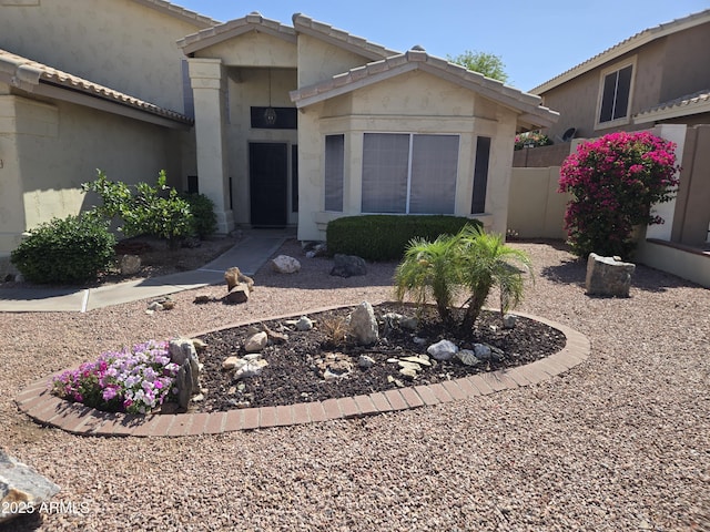 view of front of property with stucco siding, a tiled roof, and fence