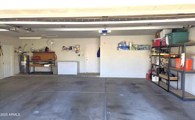 garage featuring water heater, a workshop area, refrigerator, and a garage door opener