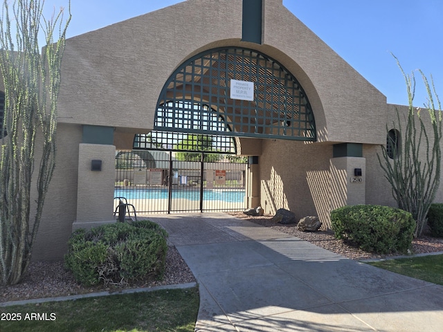 view of community with a pool, fence, and concrete driveway