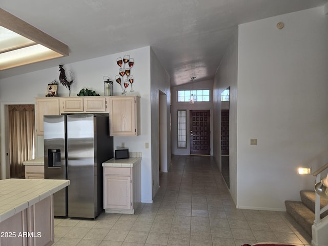 kitchen featuring tile countertops, stainless steel fridge, light tile patterned floors, baseboards, and light brown cabinetry