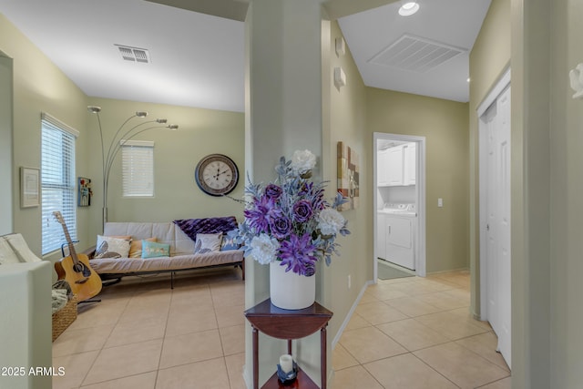 corridor featuring separate washer and dryer and light tile patterned floors