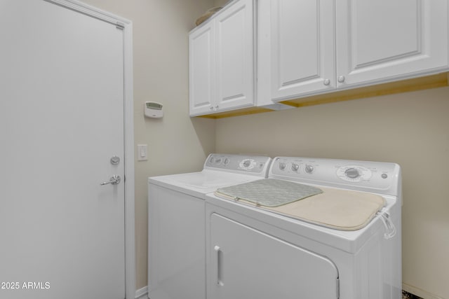 clothes washing area with cabinets and separate washer and dryer