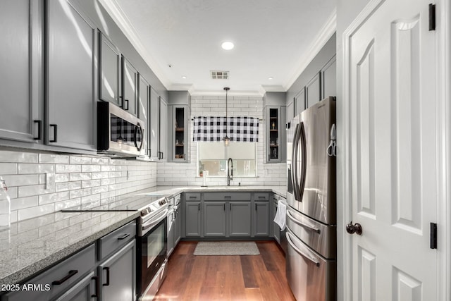 kitchen featuring gray cabinetry, hanging light fixtures, light stone countertops, and appliances with stainless steel finishes