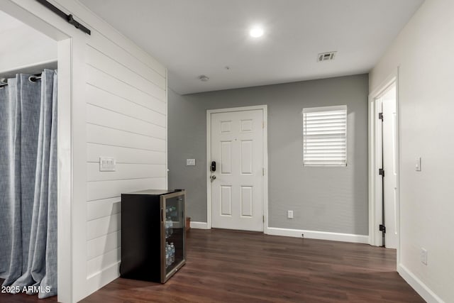 foyer entrance featuring beverage cooler, dark hardwood / wood-style floors, and a barn door