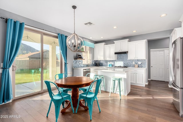 dining room with sink, a chandelier, and hardwood / wood-style flooring