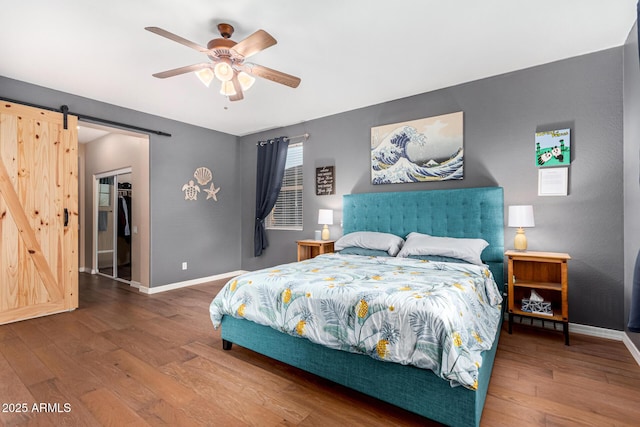 bedroom with ceiling fan, hardwood / wood-style floors, a closet, and a barn door