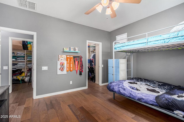 bedroom with ceiling fan, a closet, a spacious closet, and hardwood / wood-style flooring