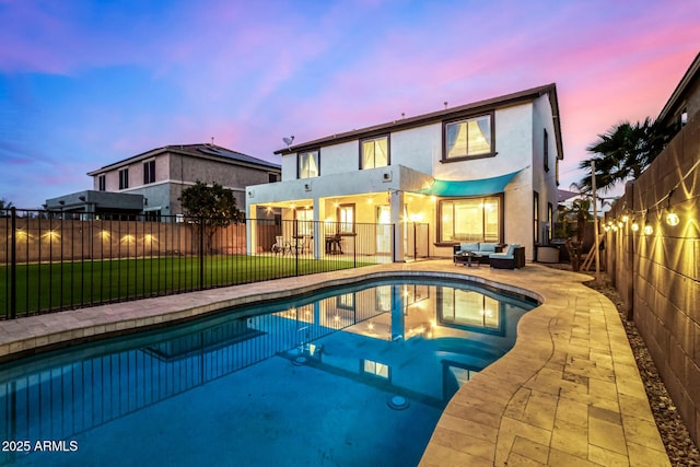 back house at dusk with a fenced in pool, outdoor lounge area, a yard, and a patio