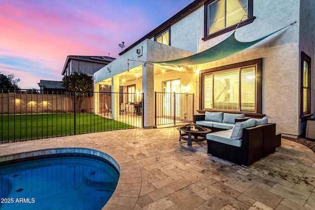 back house at dusk featuring a patio area, a fenced in pool, a yard, and an outdoor living space with a fire pit