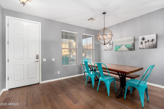 dining area with dark wood-type flooring and a chandelier