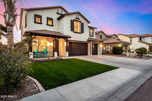 mediterranean / spanish home featuring covered porch, a yard, and a garage