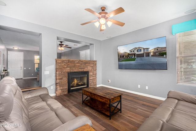 living room with dark wood-type flooring, a fireplace, and ceiling fan