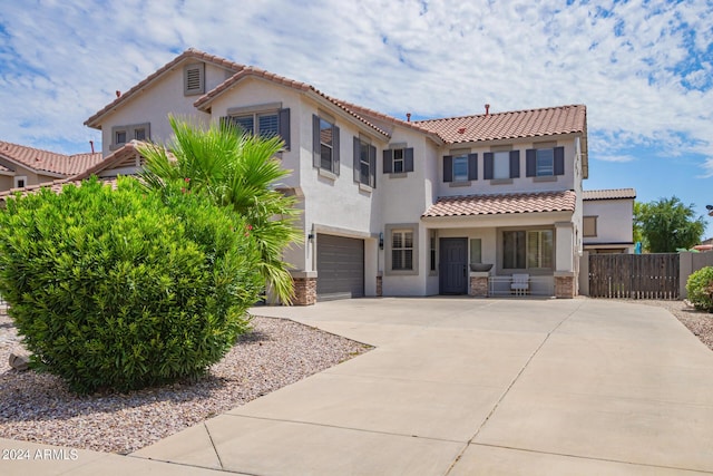 mediterranean / spanish-style house with a garage, fence, stucco siding, a tiled roof, and driveway