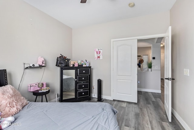 bedroom with baseboards, arched walkways, a ceiling fan, and wood finished floors