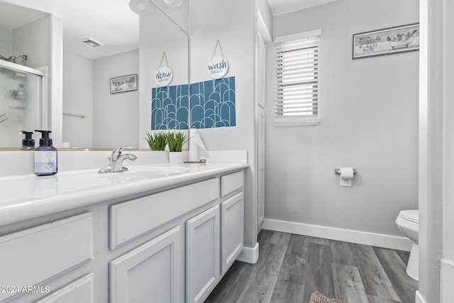 bathroom with visible vents, wood finished floors, toilet, baseboards, and a stall shower