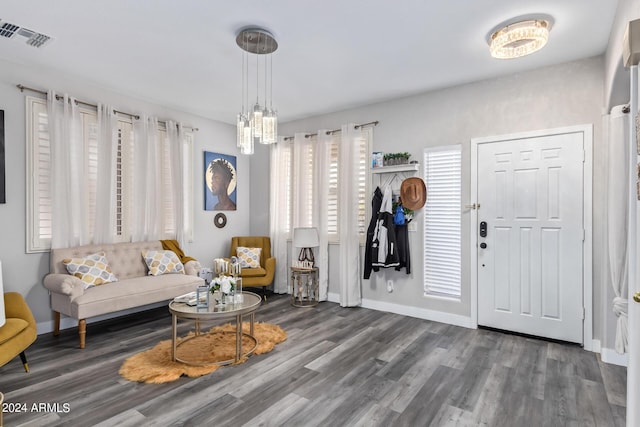 foyer featuring baseboards, a notable chandelier, wood finished floors, and visible vents