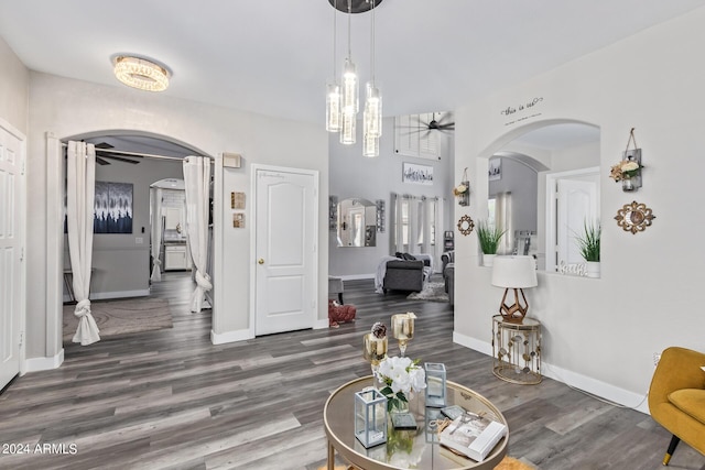 dining area featuring arched walkways, baseboards, a ceiling fan, and wood finished floors