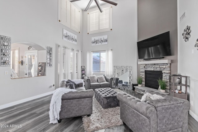 living area with a ceiling fan, a towering ceiling, visible vents, wood finished floors, and baseboards