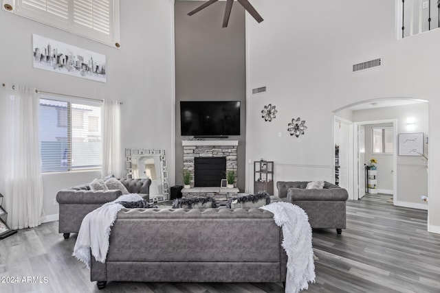 living room featuring ceiling fan, visible vents, arched walkways, baseboards, and a high ceiling
