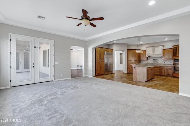 unfurnished living room featuring ceiling fan, light carpet, and french doors