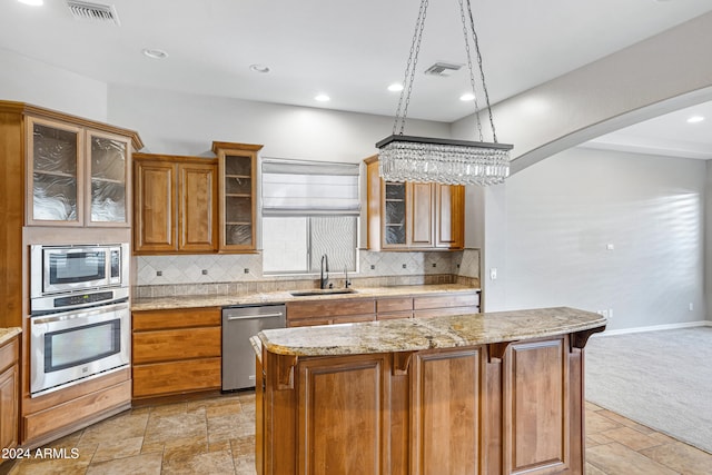 kitchen with sink, tasteful backsplash, appliances with stainless steel finishes, and a center island