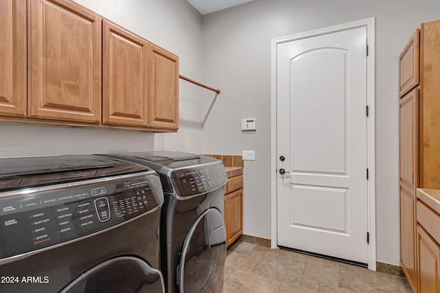 clothes washing area featuring cabinets and washing machine and clothes dryer