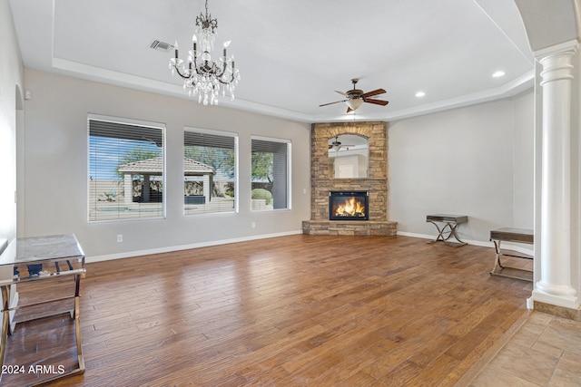 living room featuring light hardwood / wood-style floors, ceiling fan, a stone fireplace, and decorative columns