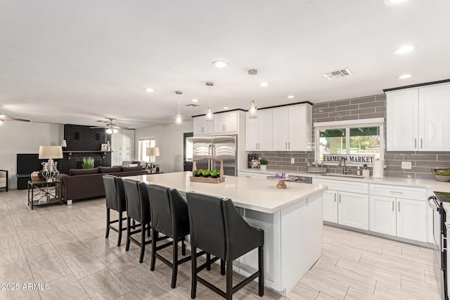 kitchen with a breakfast bar area, decorative light fixtures, appliances with stainless steel finishes, a kitchen island, and white cabinets