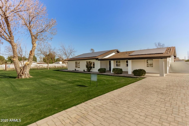 rear view of house featuring a yard and solar panels