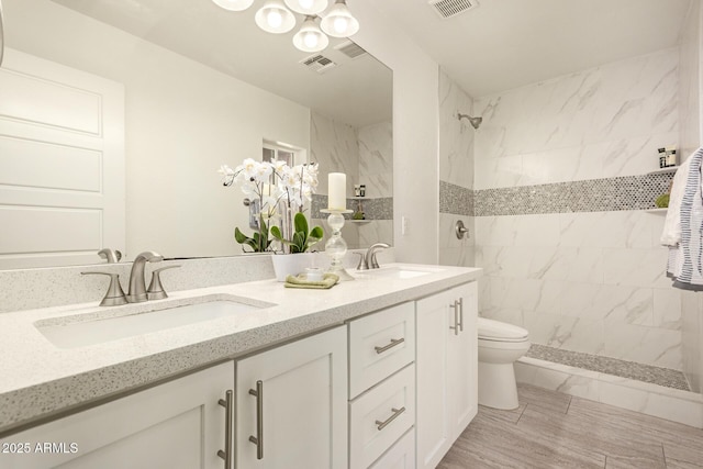 bathroom with tiled shower, vanity, and toilet