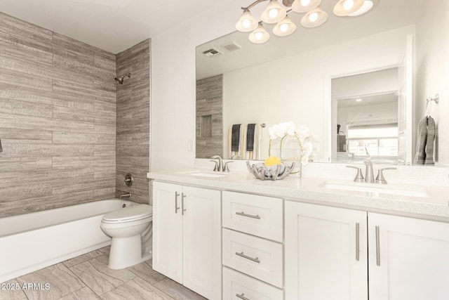 full bathroom with tiled shower / bath, vanity, and toilet