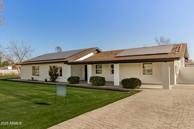 ranch-style home featuring a front yard and solar panels