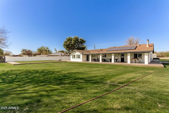 rear view of house with a lawn, a patio, and solar panels