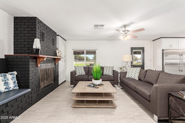 living room featuring a brick fireplace and ceiling fan