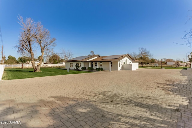 ranch-style home with a front yard and solar panels