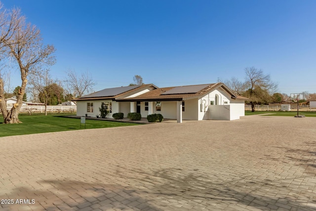 ranch-style home featuring a front lawn and solar panels