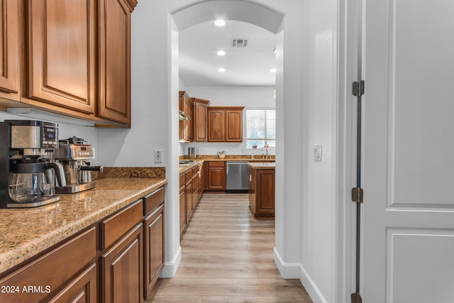 kitchen with light stone counters, light hardwood / wood-style flooring, and dishwasher