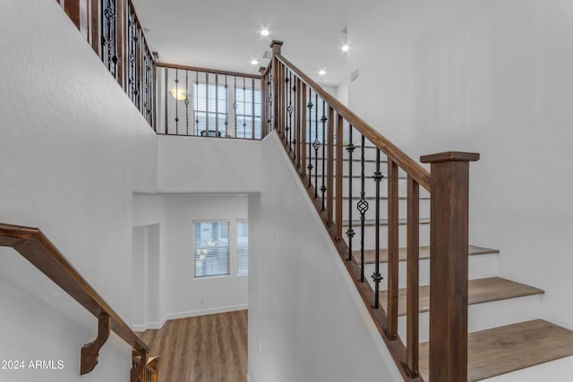 staircase with a towering ceiling and hardwood / wood-style floors